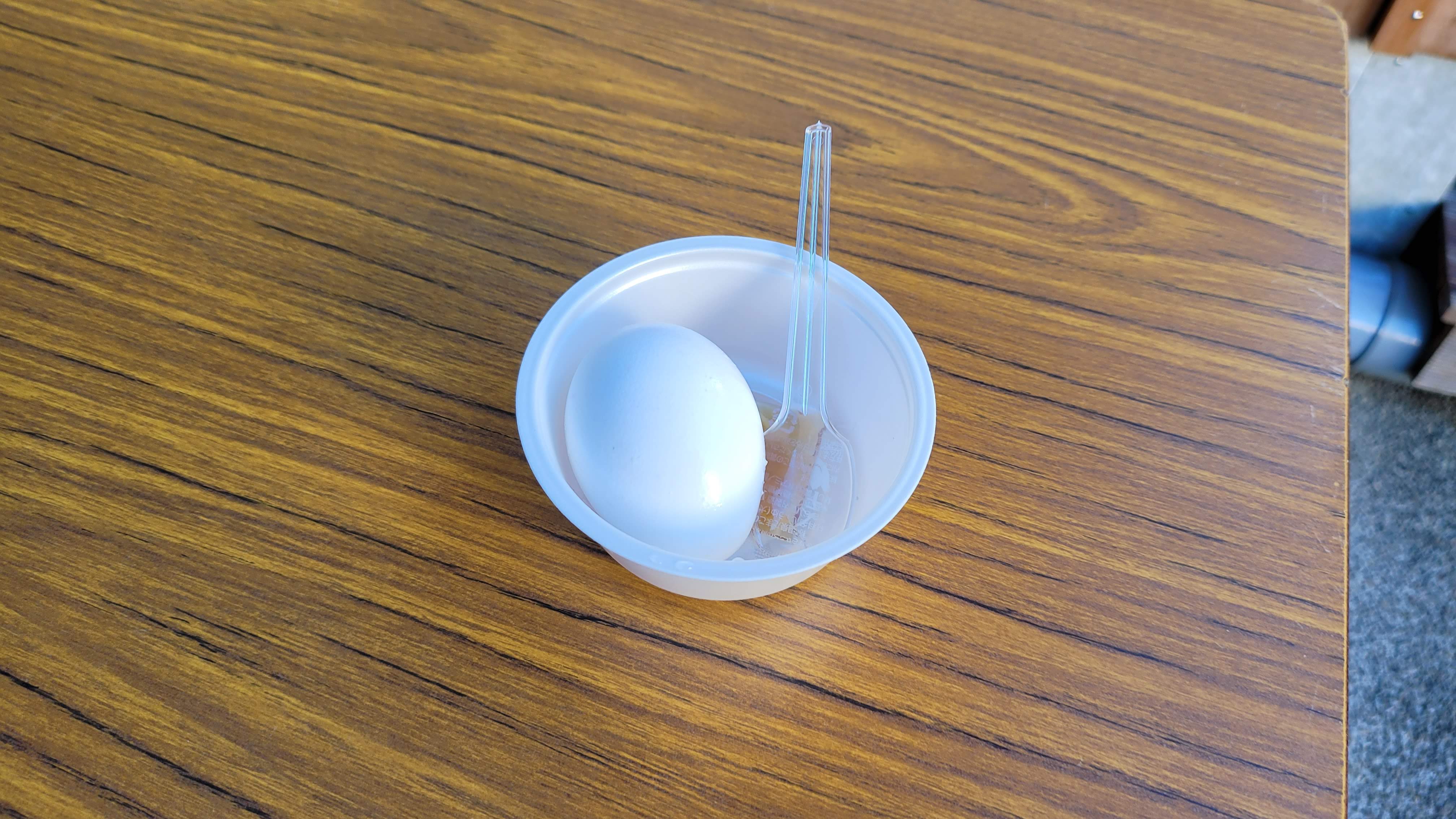 ไข่ต้มน้ำพุร้อน (Onsen tamago) ไข่สุกในชามขาวพลาสติกพร้อมช้อนพลาสติก — ของว่างเบาๆ จากน้ำพุร้อนธรรมชาติ