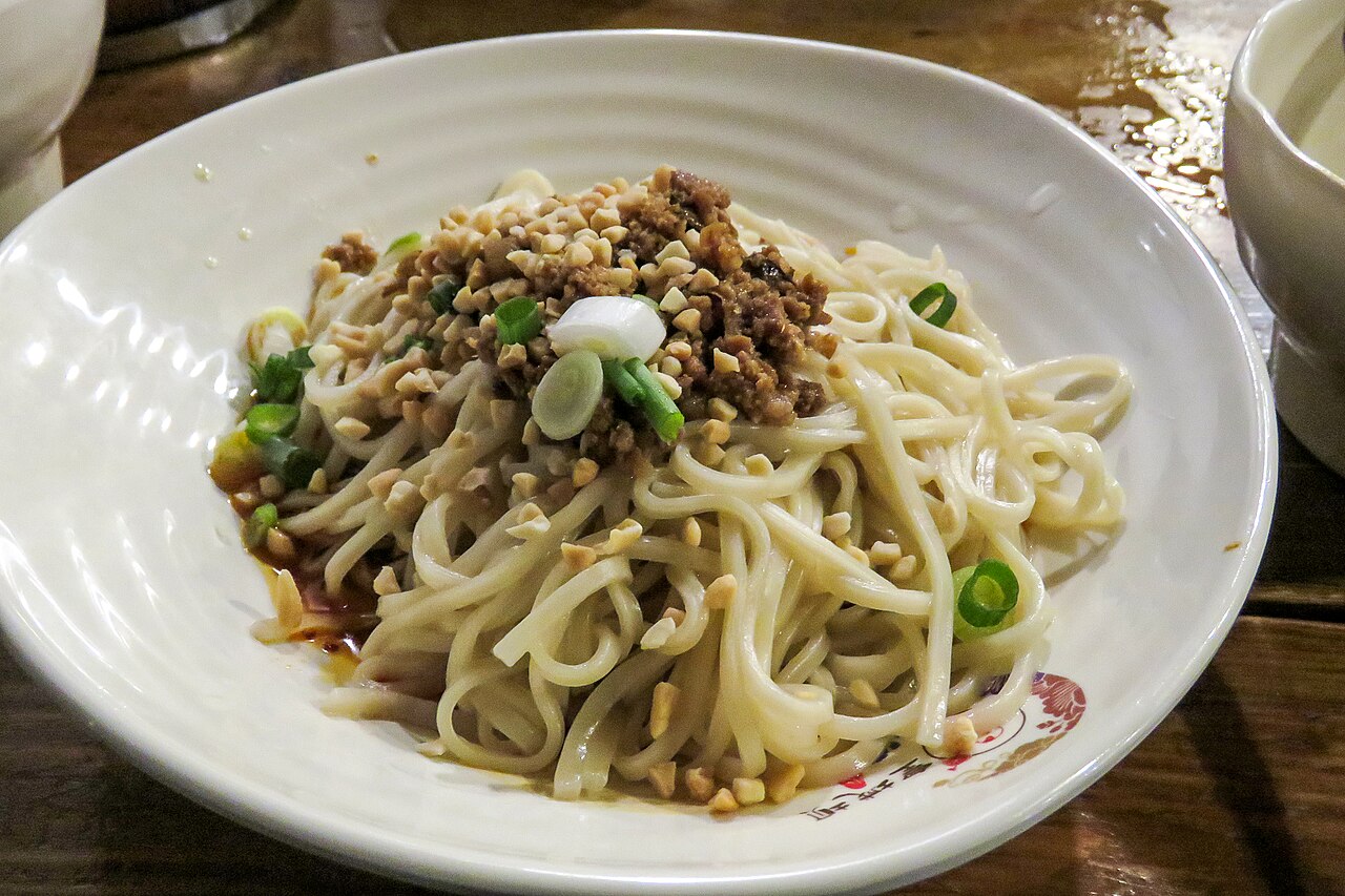 บะหมี่ตันตัน บะหมี่แห้งโรยหมูสับกรอบ ถั่วลิสงบด ต้นหอมซอย มีน้ำพริกแดงอยู่ก้นชาม
