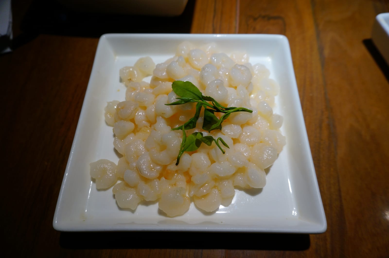 龙井虾仁 หลงจิ่งเซียเหริน กุ้งแม่น้ำตัวเล็กสีขาวอมชมพูกองบนจานขาว มีใบชาเขียวหลงจิ่งสดวางแซมด้านบน ไม่มีซอสข้น