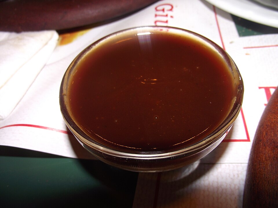 A bottle of deep-red BBQ sauce and a dish of sauce