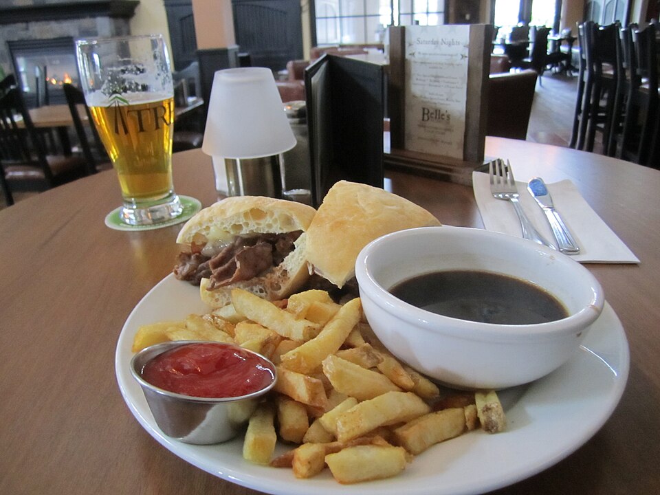 แซนด์วิช French dip เนื้อหั่นบางในขนมปังเสิร์ฟพร้อมถ้วยน้ำเกรวีจุ่ม