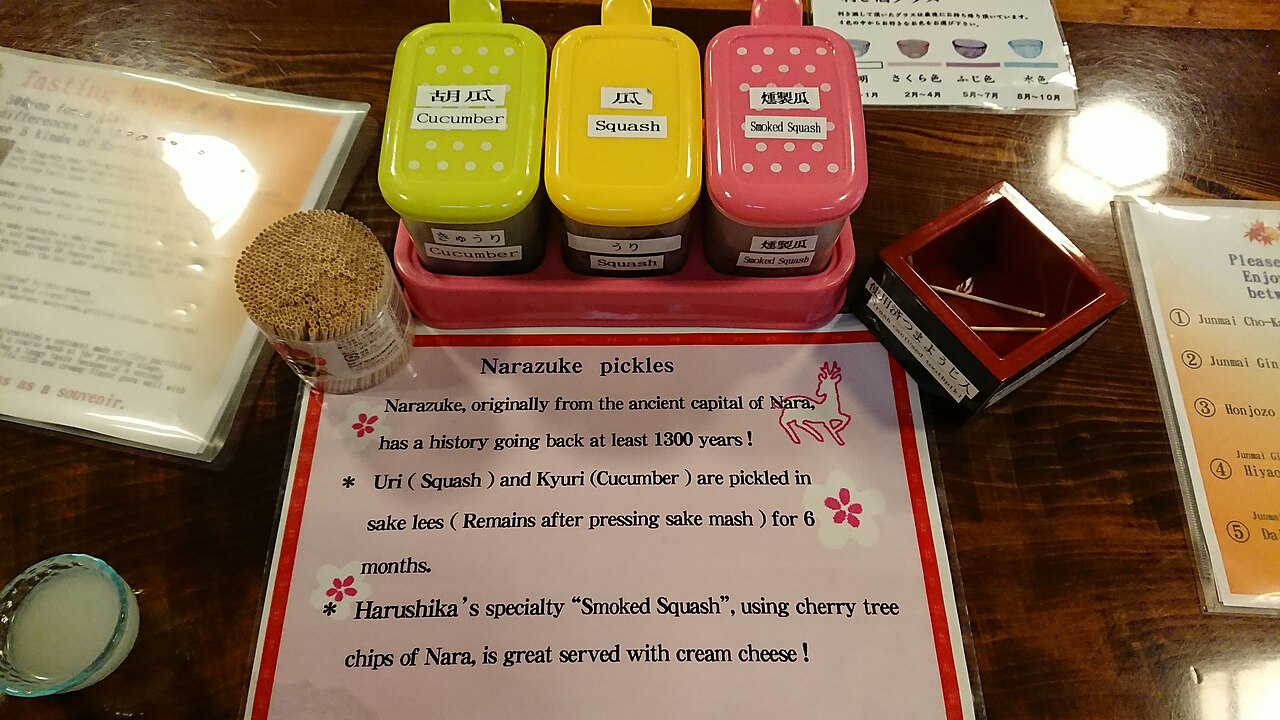 Narazuke ผักดองน้ำสาเกนาราในกล่องสุ่มสีเหลืองและชมพู มีป้ายอธิบายภาษาอังกฤษว่า Cucumber, Squash, Smoked Squash จาก Harushika Sake Brewery