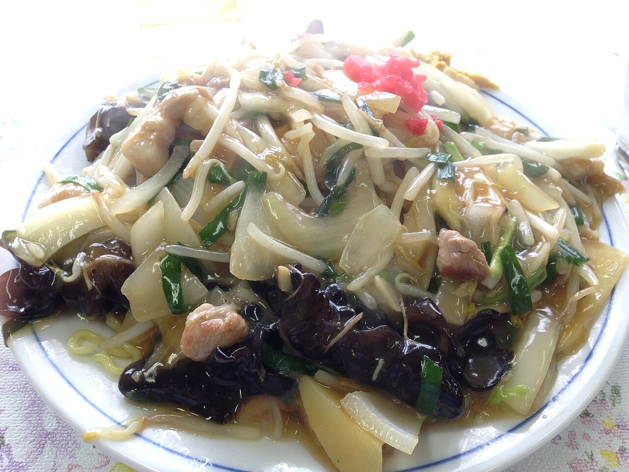 อังกะเกะยากิโซบะโอตารุ — เส้นผัดกรอบราดซอสข้นสีน้ำตาลทอง ผสมผักและหมู เสิร์ฟในจานเซรามิกขาวริมน้ำเงิน