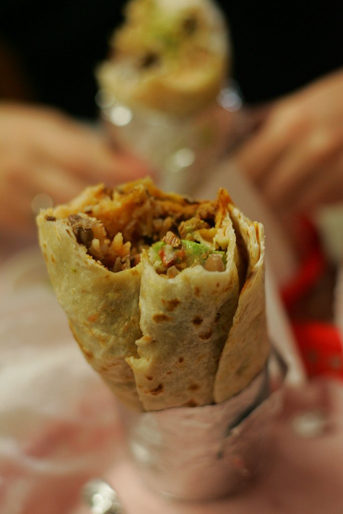 A large foil-wrapped Mission burrito cut in half showing rice, beans, and meat