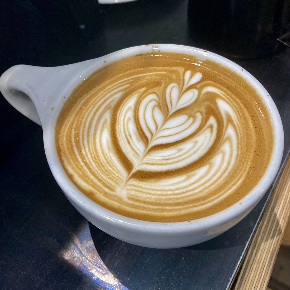 กาแฟลาเต้ลายดอกไม้บนผิวในแก้วเซรามิก