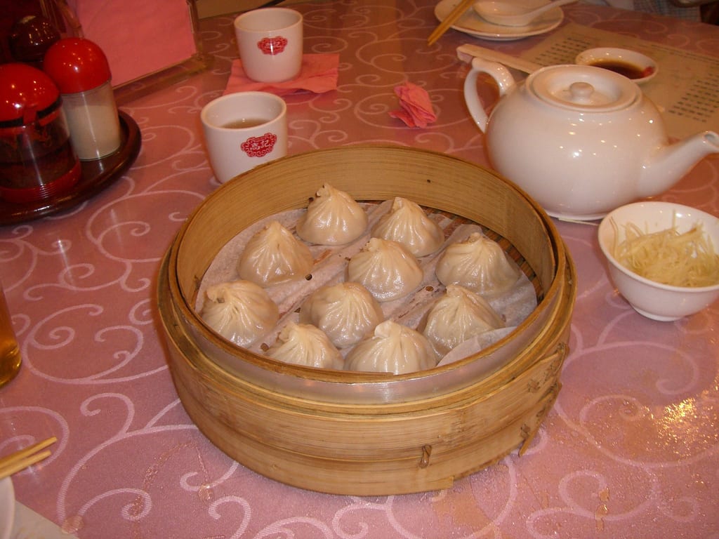 A bamboo steamer of xiaolongbao soup dumplings on Yongkang Street, Taipei, the pleated skins resting on a leaf