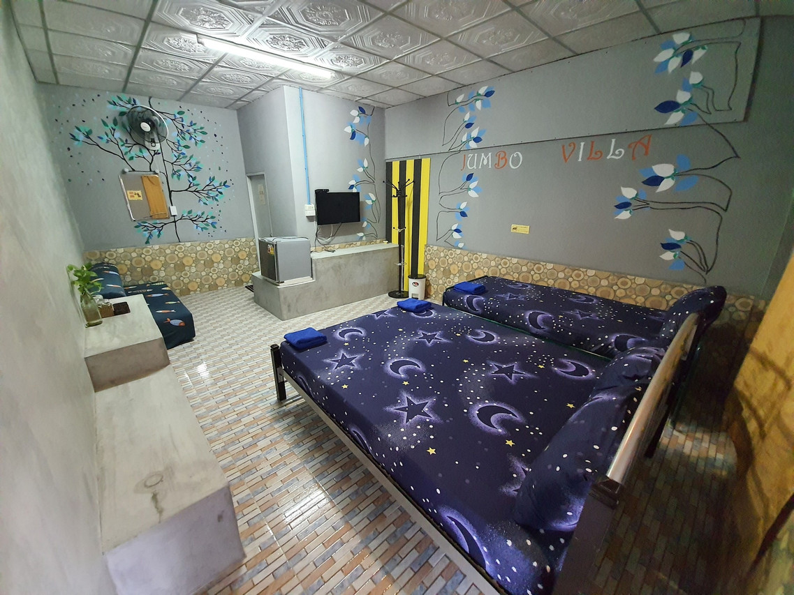 ห้องพักตกแต่งผนังลายต้นไม้กับชื่อ Jumbo Villa เตียงคู่ในห้องสไตล์ปูนเปลือย