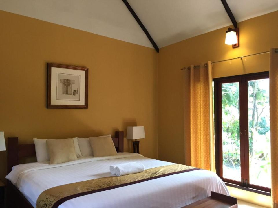 Thai villa bedroom with mustard walls and doors opening to the garden