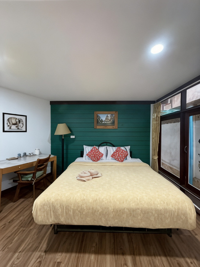 ห้องพักผนังไม้ทาสีเขียว เตียงคลุมผ้าไหม โต๊ะทำงานไม้ ของ Tamarind Guesthouse