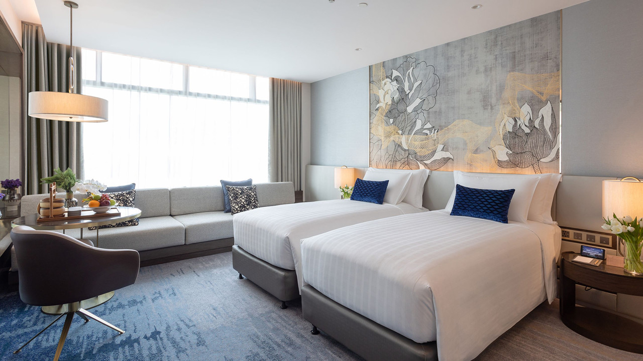 ห้อง Deluxe ของ Chatrium Grand Bangkok โทนสีฟ้าเทา มีภาพดอกบัวเหนือหัวเตียง