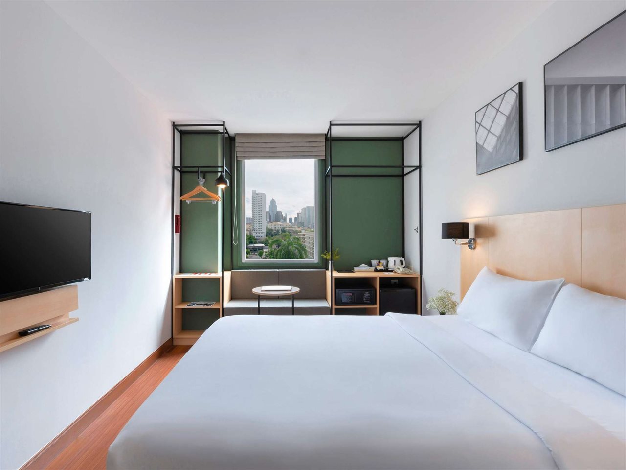 Superior room at ibis Bangkok Sukhumvit 4 with double bed, green accent wall and Sukhumvit skyline view