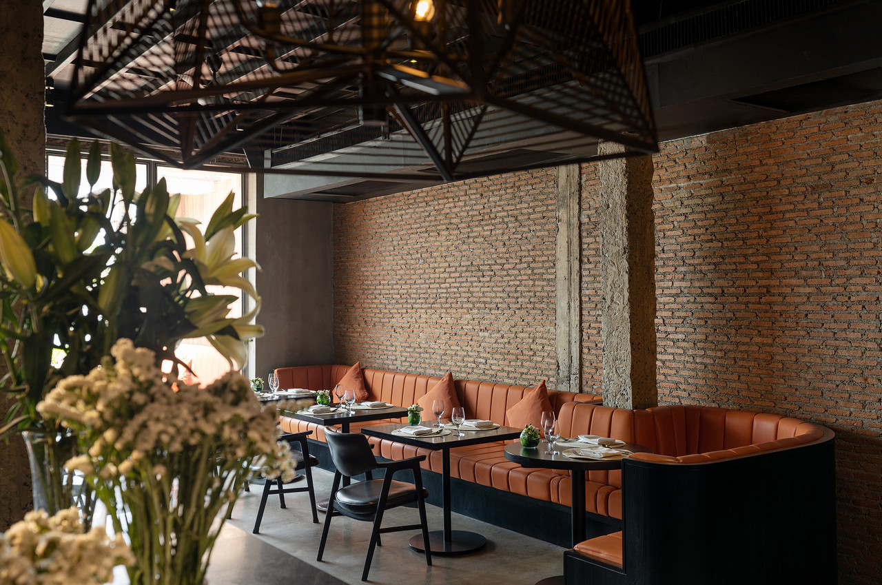Eatery interior with raw brick wall and exposed concrete beams at Sala Rattanakosin