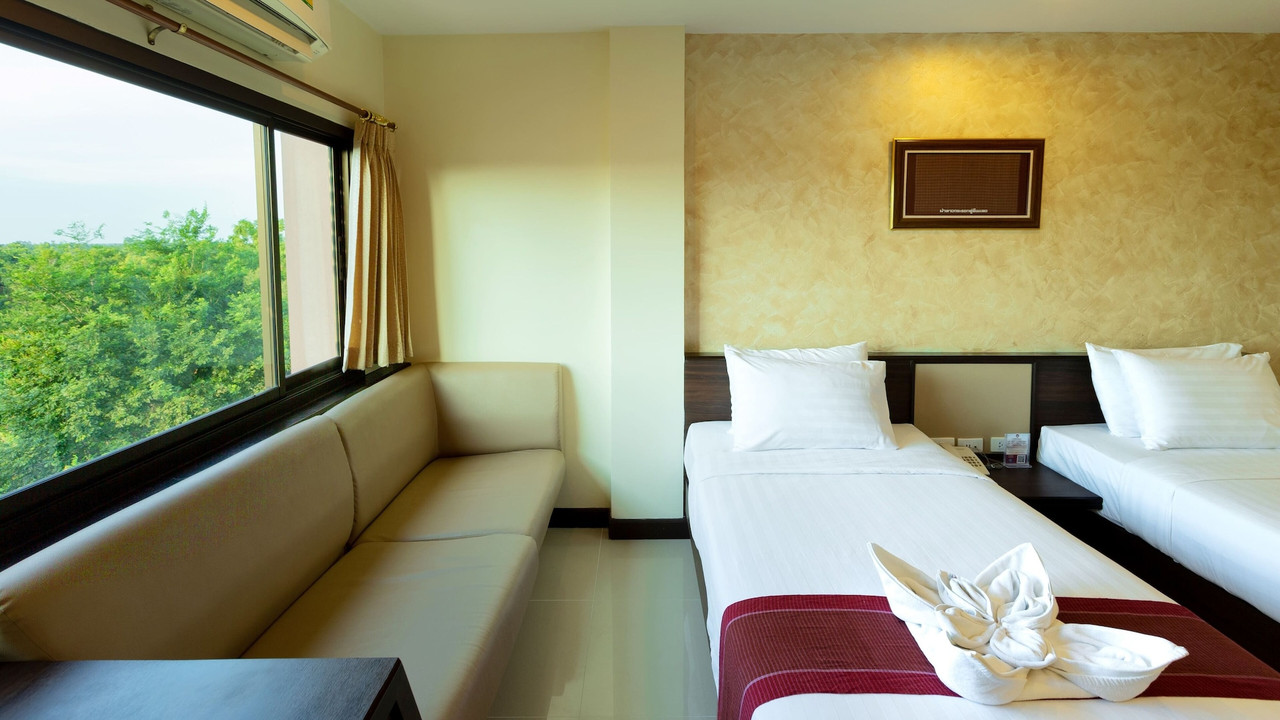 ห้องพักโทนอุ่นมีโซฟาริมหน้าต่างวิวสวน Phanomrungpuri Hotel