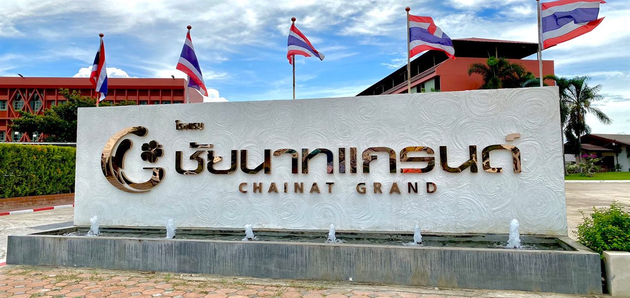 ป้ายชื่อโรงแรมชัยนาทแกรนด์ พร้อมน้ำพุและธงชาติด้านหน้า