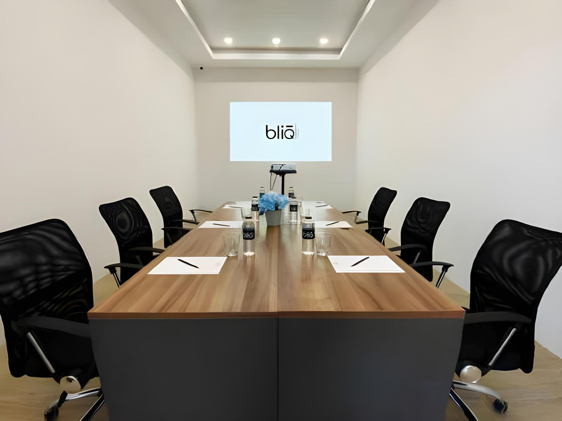 ห้องประชุมโต๊ะไม้ยาว เก้าอี้ทำงาน จอโปรเจกเตอร์โลโก้ bliQ