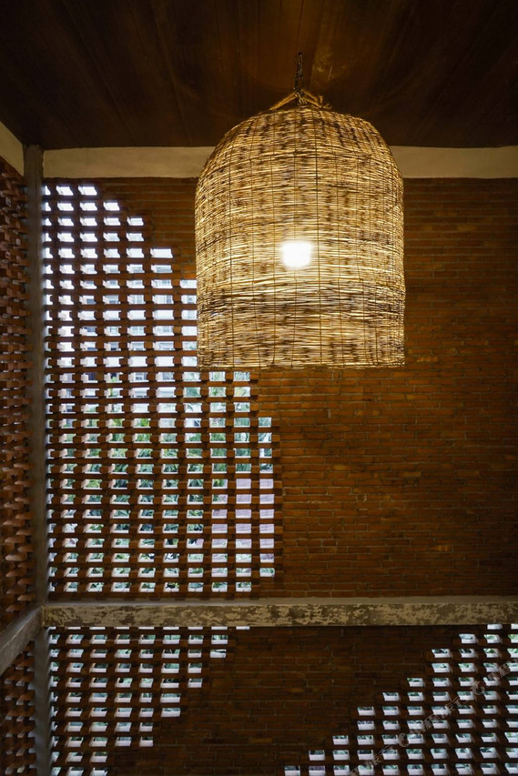 Lanna-style perforated brick wall with rattan pendant lamp