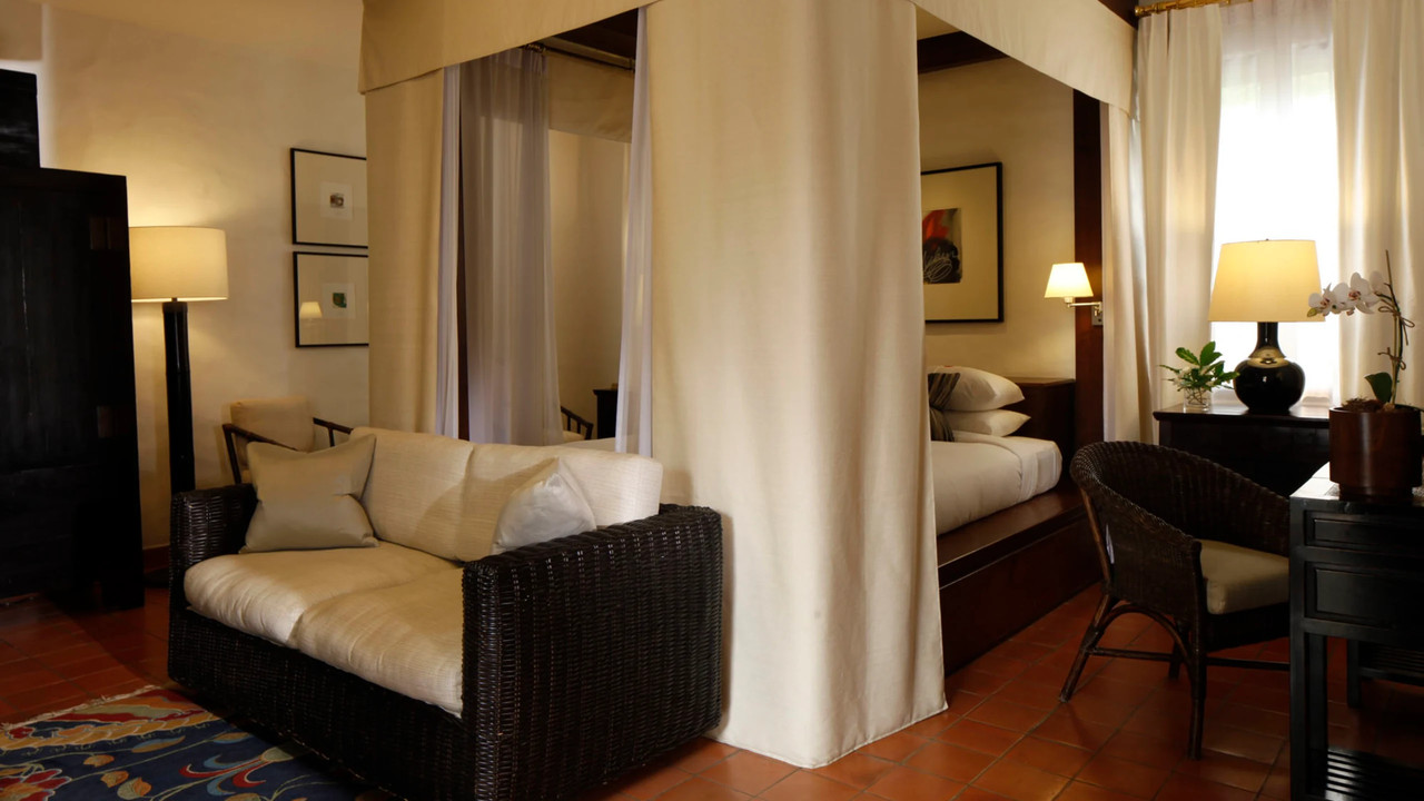 Guest room with four-poster teak bed and terracotta floor