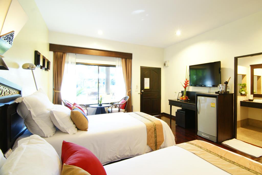 Lanna-style bungalow room with teak floors, twin beds and a garden-facing balcony