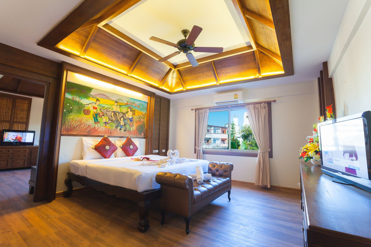 Suite with carved teak ceiling and a Thai mural above the bed