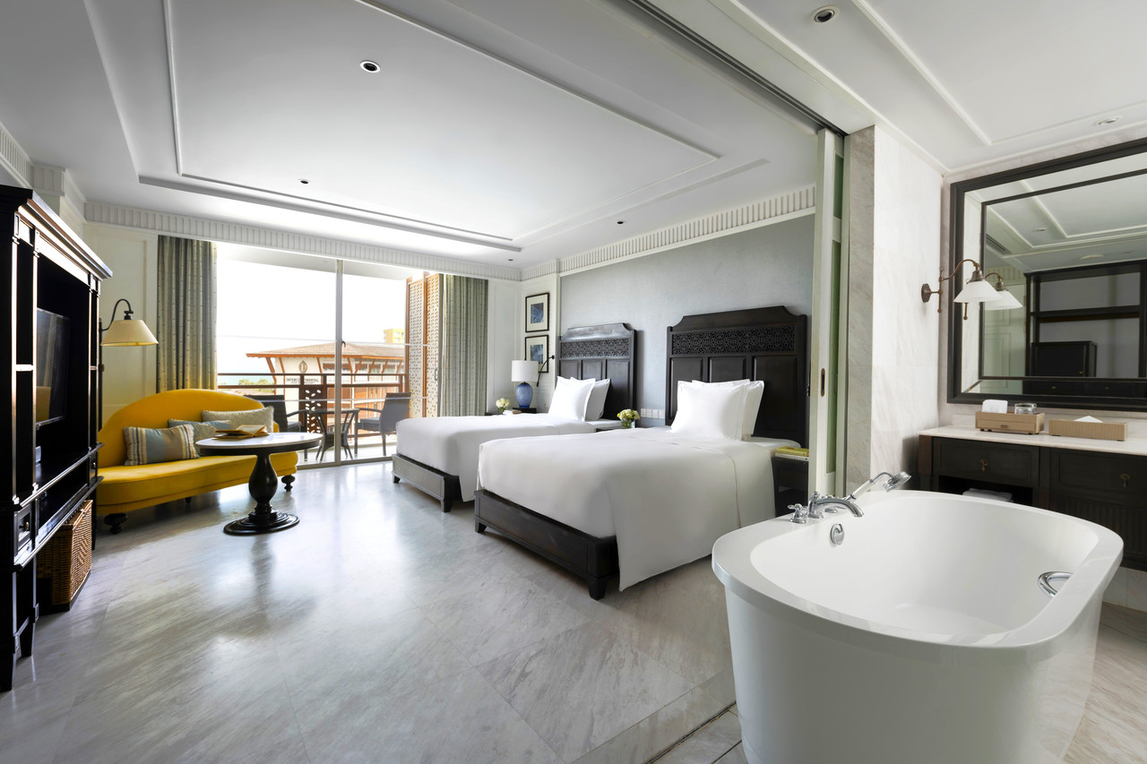 Twin guest room in Colonial dark-wood design with freestanding tub and balcony