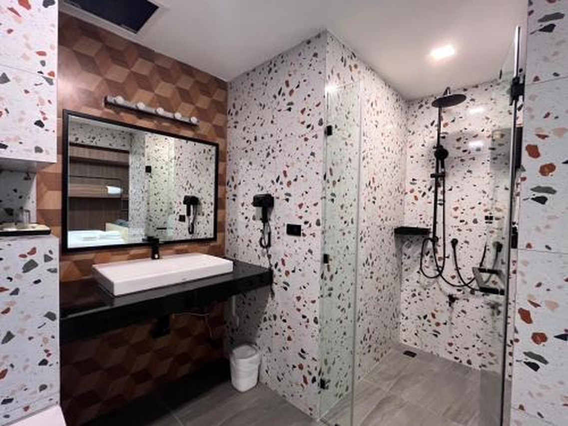 ห้องน้ำหินขัดของ J2 Hotel พร้อมฝักบัวเรนชาวเวอร์และกระจกใส