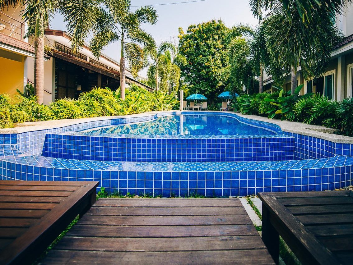 Blue-tiled outdoor pool and palm garden at Good Times Resort Kanchanaburi