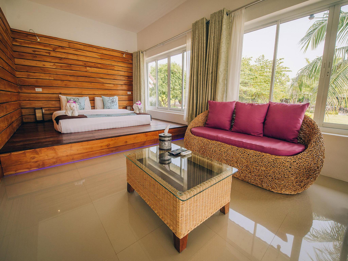 Spacious wood-panelled room with a wicker sofa and garden-view windows