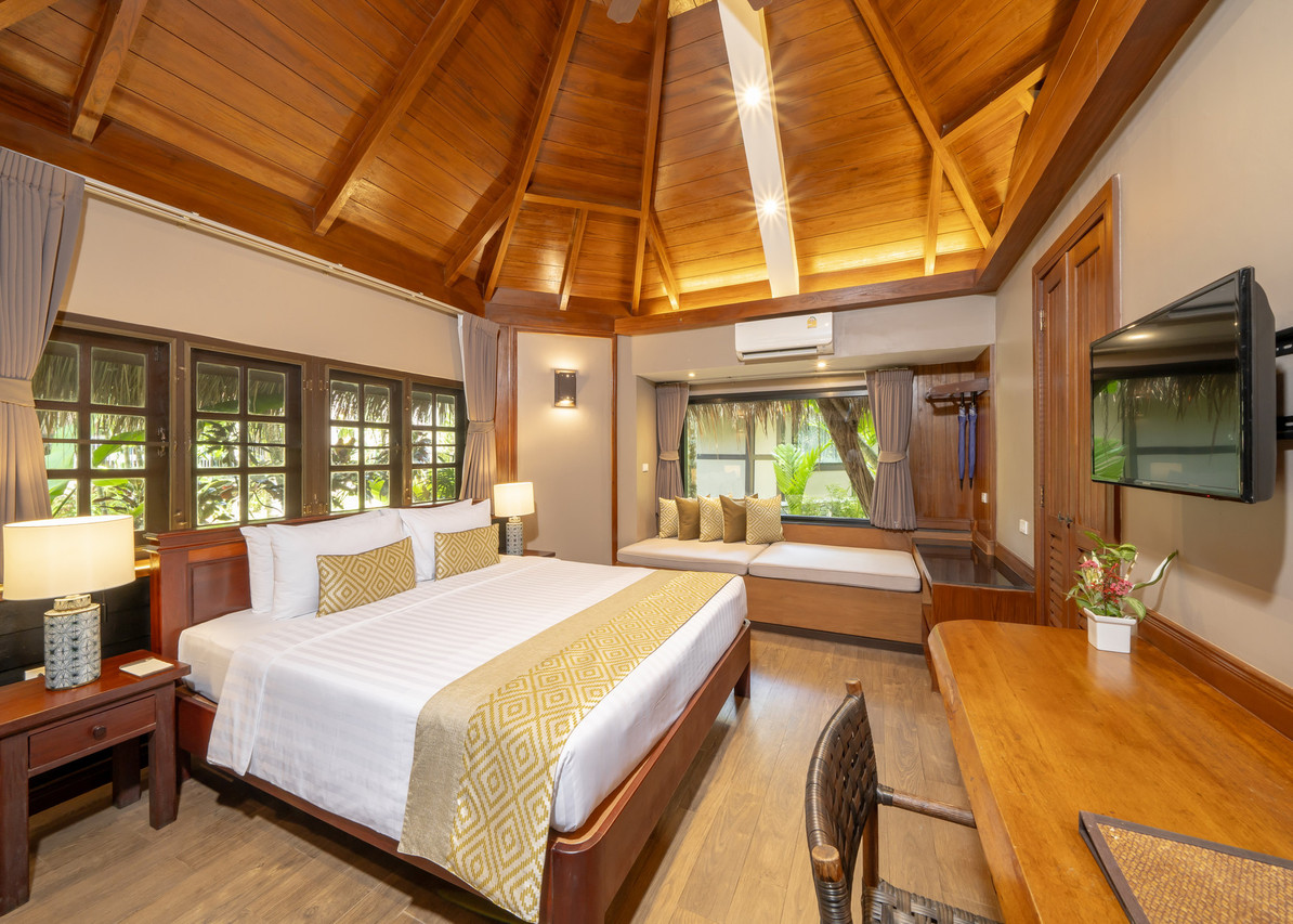 Bungalow interior with a tall pitched teak ceiling, bed and window seat