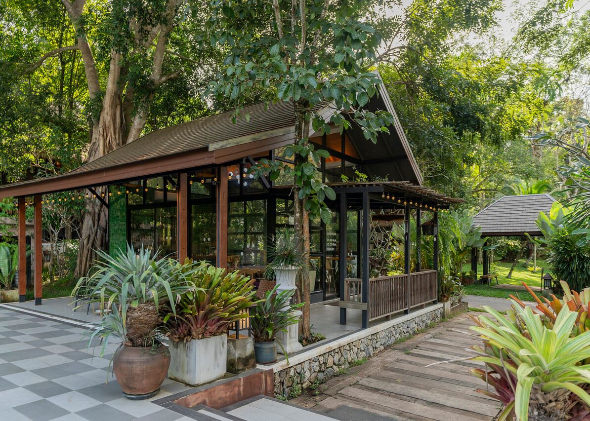 Jungle-style restaurant with timber roof and a stone terrace under large trees