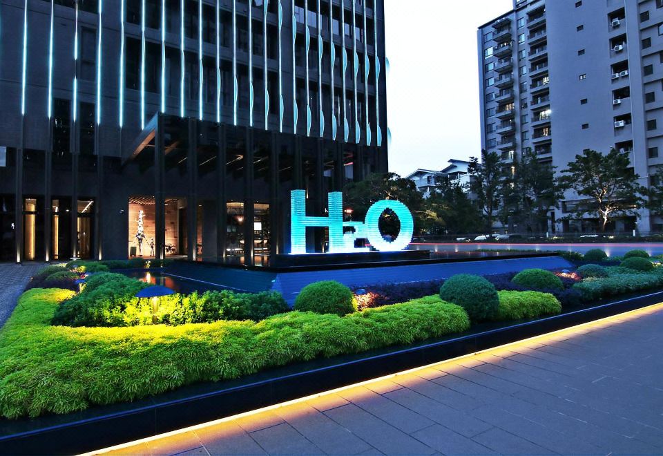 ทางเข้า H2O Hotel Kaohsiung ยามค่ำคืน อักษร H2O เรืองแสงในสวนหน้าโรงแรม