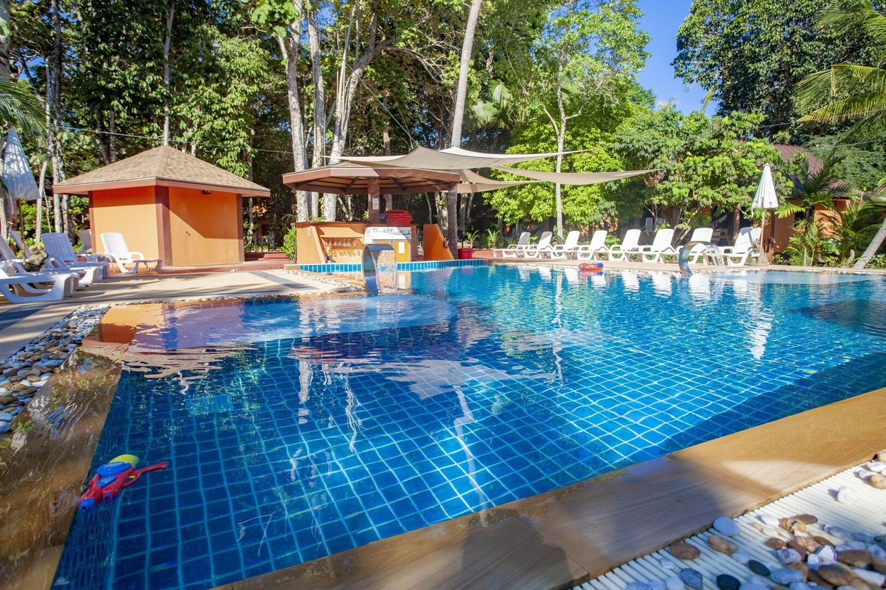 สระว่ายน้ำกลางแจ้งพร้อม Pool Bar กลางสวนปาล์มที่ Lanta Pearl Beach Resort