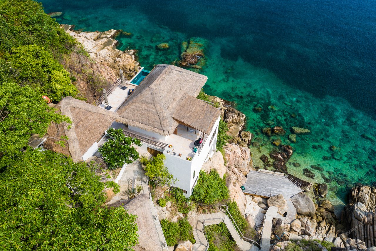Aerial of a thatched clifftop villa above the clear water of Shark Bay