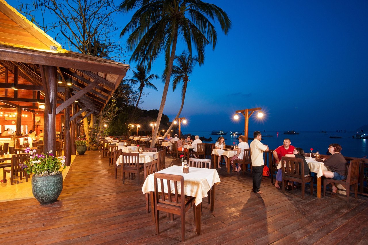 ร้านอาหารไทยริมทะเลของรีสอร์ตช่วงพลบค่ำ มองเห็นอ่าวและเรือ