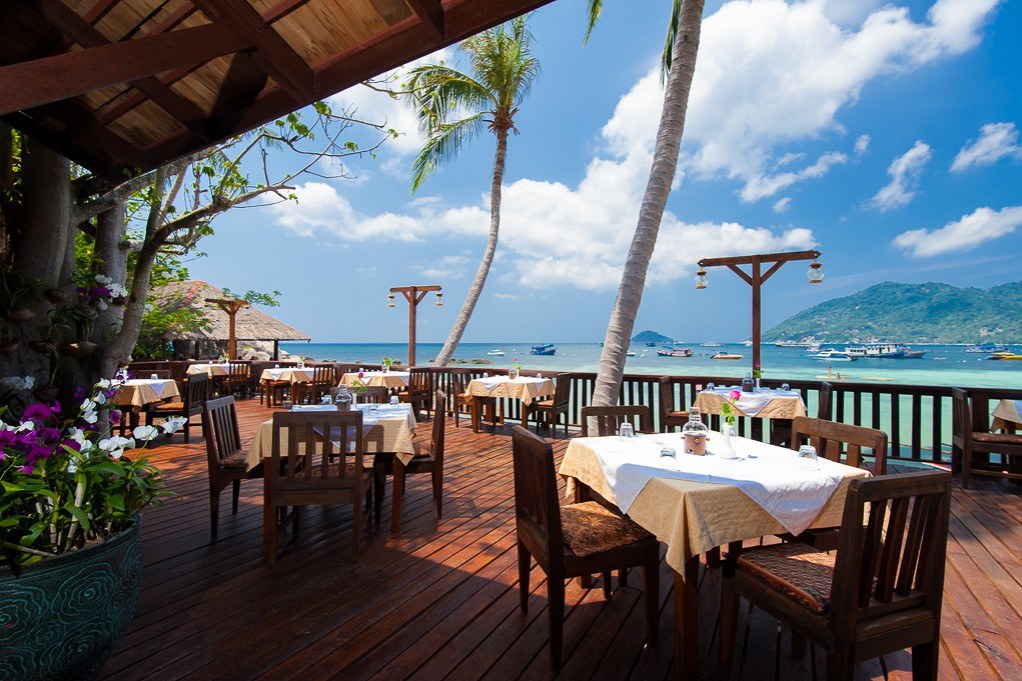 Seafront restaurant deck with wooden tables overlooking Mae Haad bay and the pier