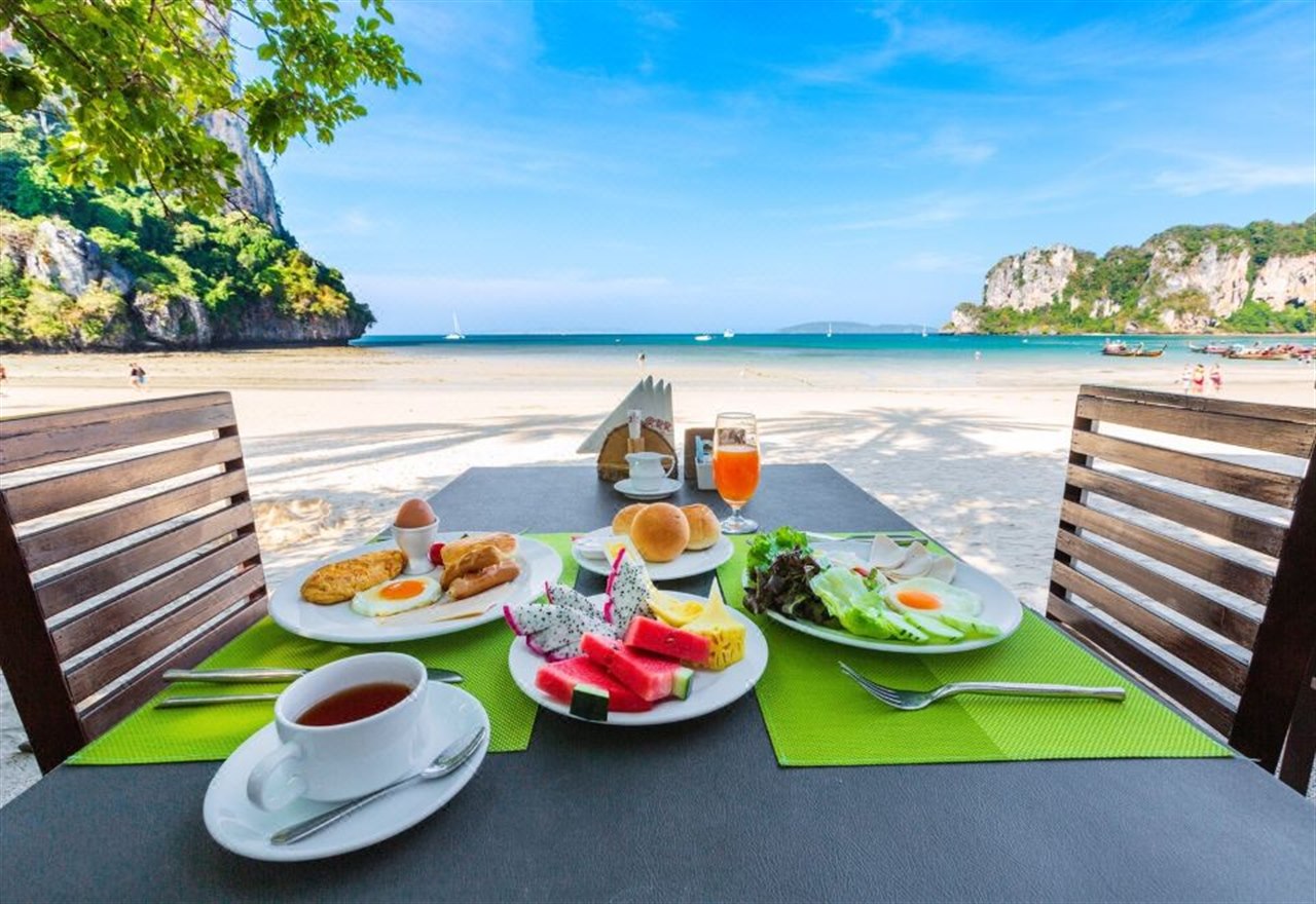 Beachfront breakfast table on Railay Beach overlooking the bay and longtail boats