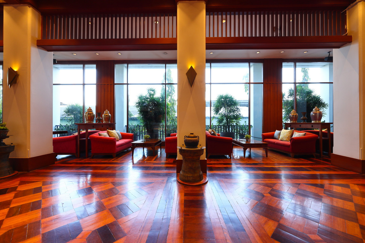 มุมนั่งเล่นในล็อบบี้ Wienglakor Hotel โซฟาแดงกับหน้าต่างมองสวน