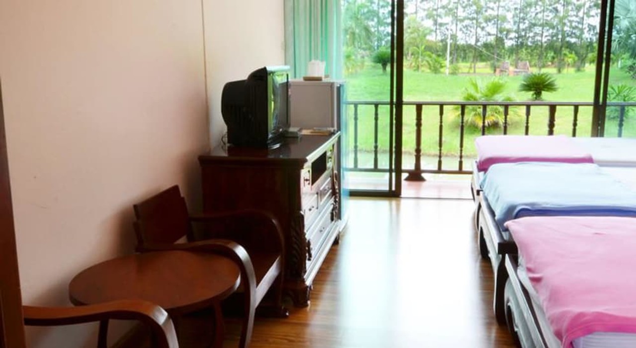 ห้องพักพร้อมระเบียงมองออกไปเห็นสนามหญ้ากว้างและสวนปาล์ม