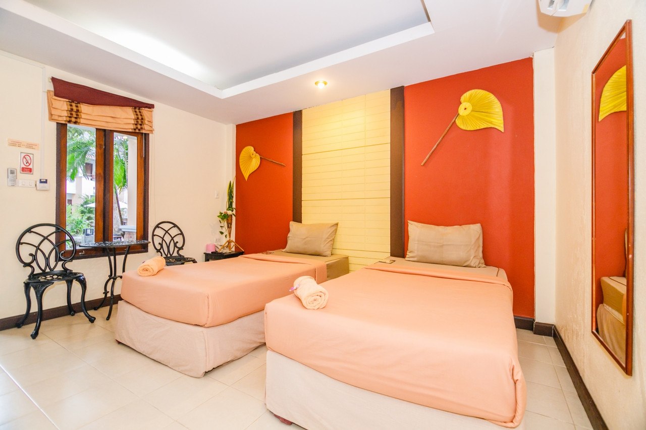 ห้องเตียงคู่ ผนังสีดินเผา ตกแต่งพัดใบลานสีเหลือง วิวสวนที่ Huandalha Resort ลำพูน