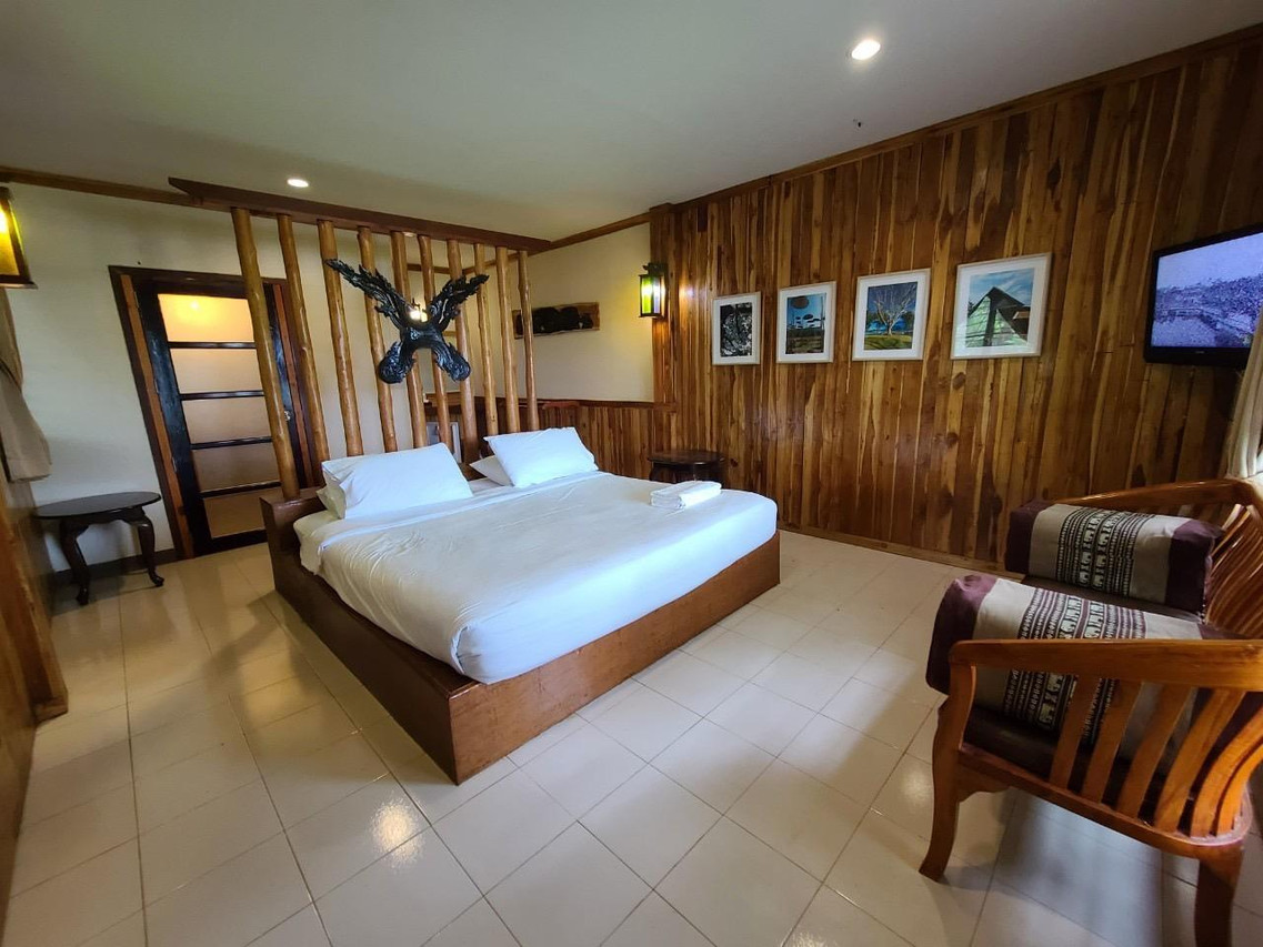 Teak-panelled guest room with bed and framed wall photos