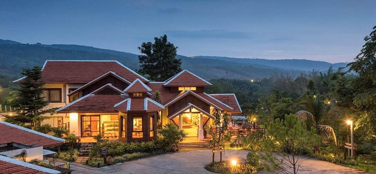 อาคารต้อนรับเรือนไม้ของ Phunacome Resort ยามค่ำ มีภูเขาเป็นฉากหลัง