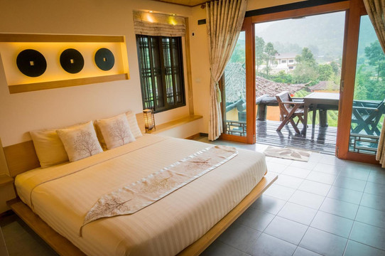 Warm wood-toned guest room with a private balcony over the mountains and tea terraces