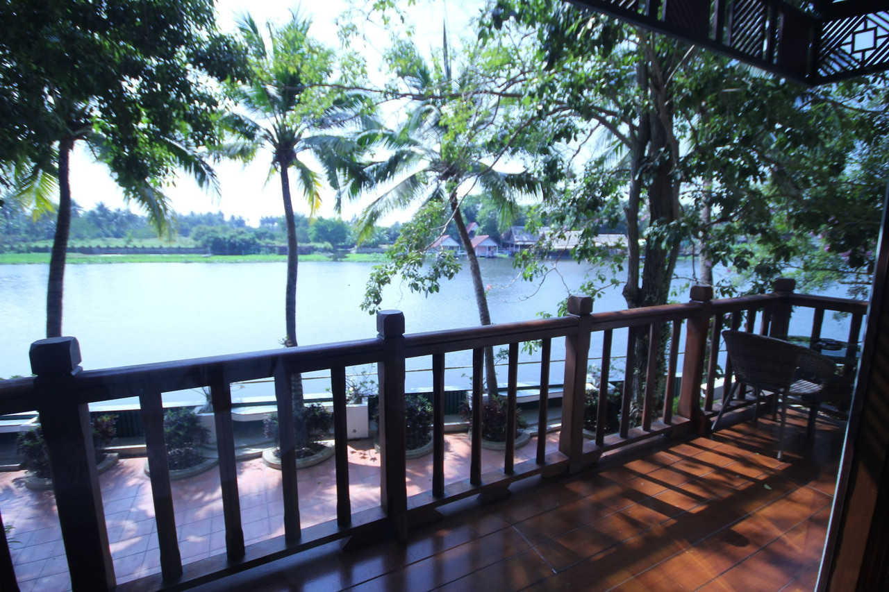 ระเบียงไม้วิวแม่น้ำท่าจีนพร้อมต้นมะพร้าวที่ RK Riverside Resort นครปฐม