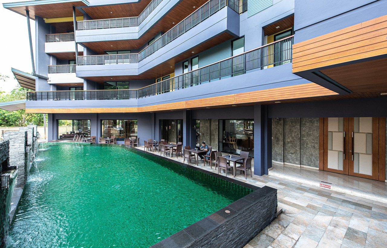 สระว่ายน้ำกลางแจ้งริมห้องอาหารที่ The Proud Exclusive Hotel นครปฐม มีโต๊ะนั่งริมสระ