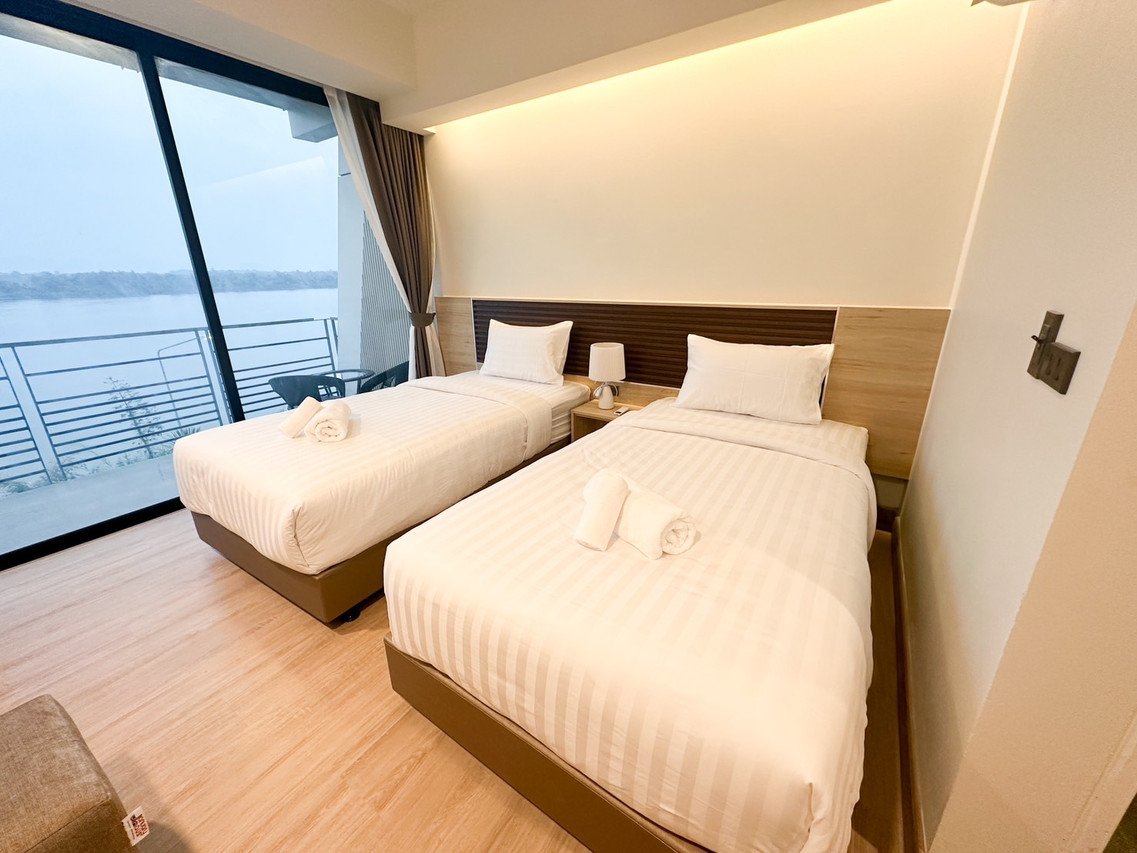 ห้องเตียงคู่ของ Mekong Pano Villa ประตูกระจกออกระเบียงเห็นแม่น้ำโขงและฝั่งลาว