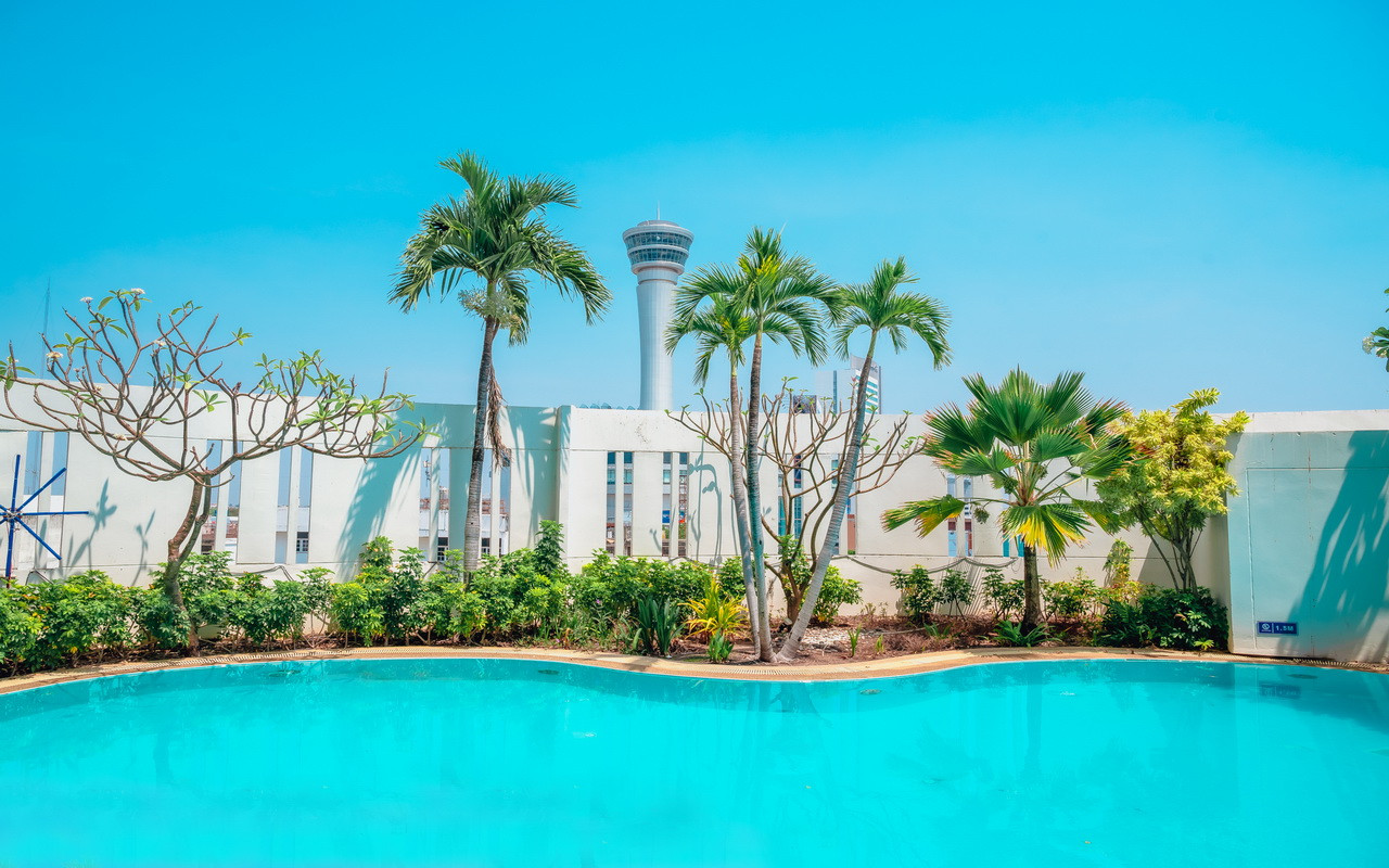 Outdoor swimming pool at Fortune Hotel Korat with palm trees and a tower view