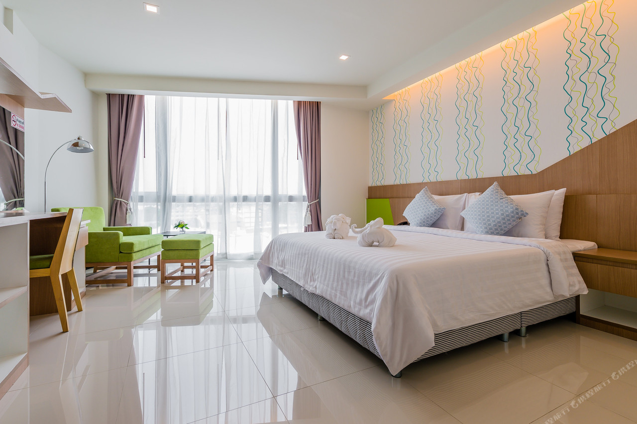 ห้องเตียงคิงของ 42C The Chic Hotel พื้นกระเบื้องขาว โซฟาสีเขียว ระเบียงกระจกบานใหญ่