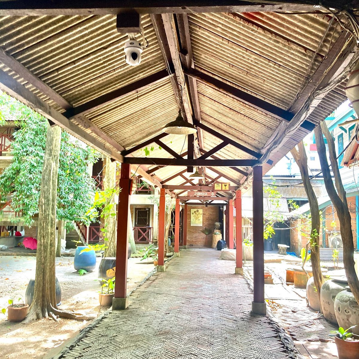 ทางเดินมีหลังคาคลุมผ่านสวนต้นไม้ใหญ่ในโรงแรม