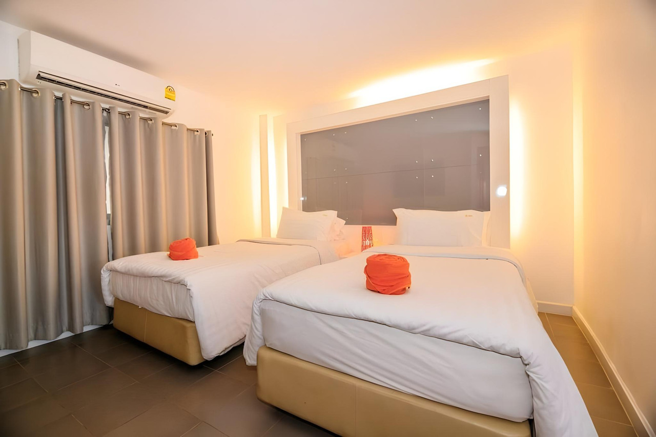 ห้องพักเตียงคู่ของ The Original Orange Hotel ผ้าเช็ดตัวม้วนสีส้มบนเตียง