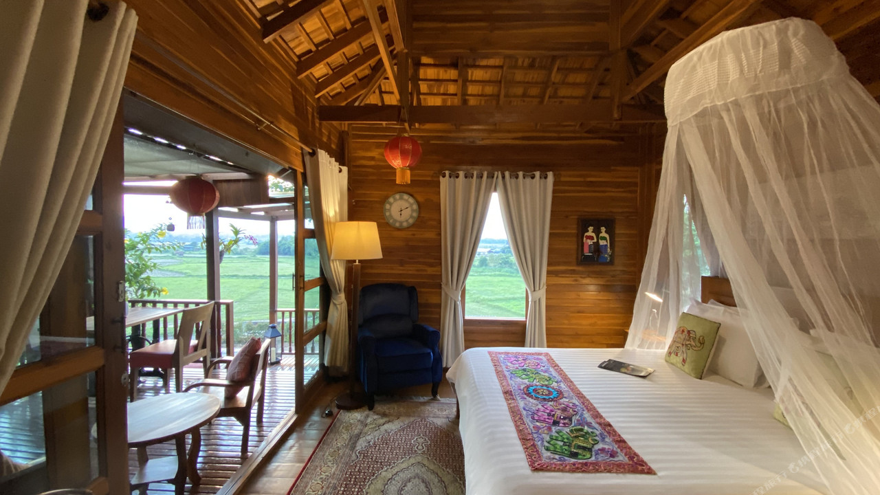 Teak bungalow interior with mosquito-net bed and a balcony over the rice fields