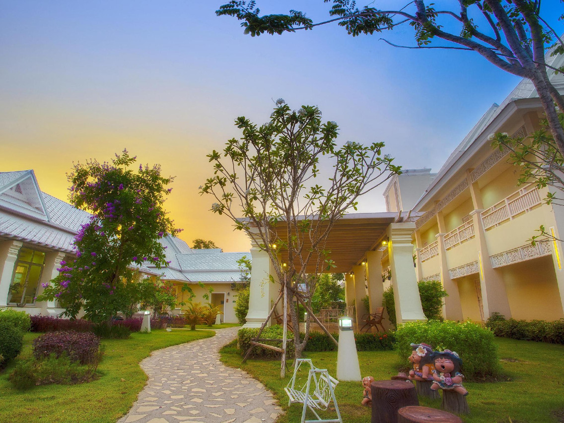 สวนสไตล์ล้านนาของ Nantrungjai ยามเย็น มีตุ๊กตาประดับและทางเดินหิน